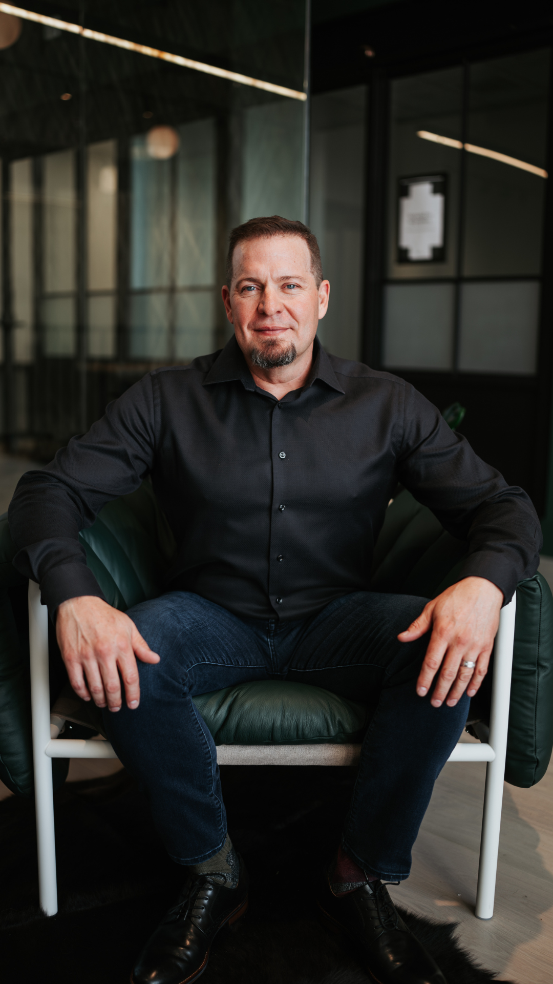 Adam Feuerstein mentor and personal transformation coach seated in modern office, guiding clients to release the mask, reclaim their voice, and live authentically