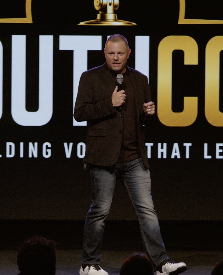 Matt Adkins speaking on stage at YouthCon