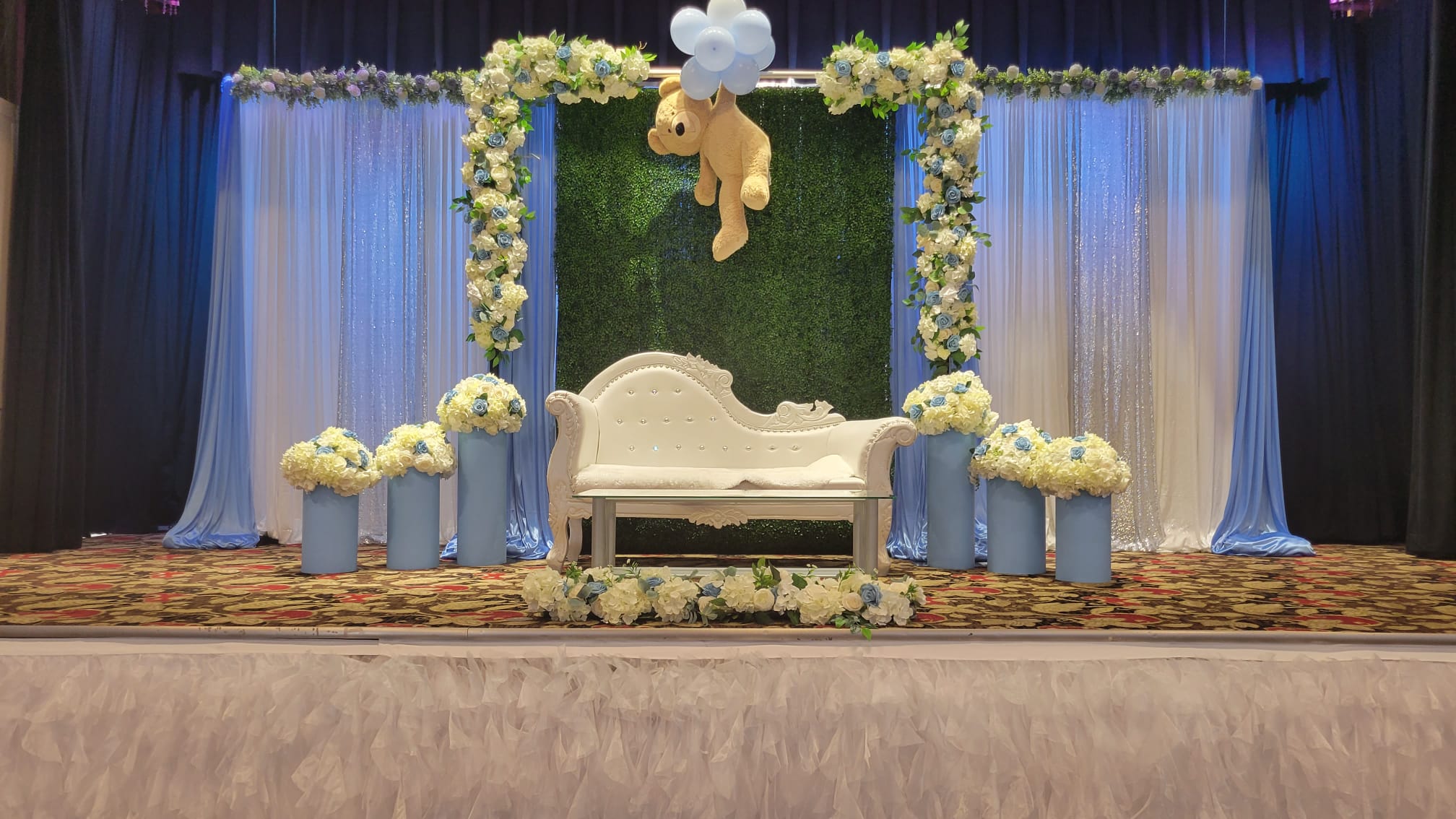 A white and green floral stage behind the head table