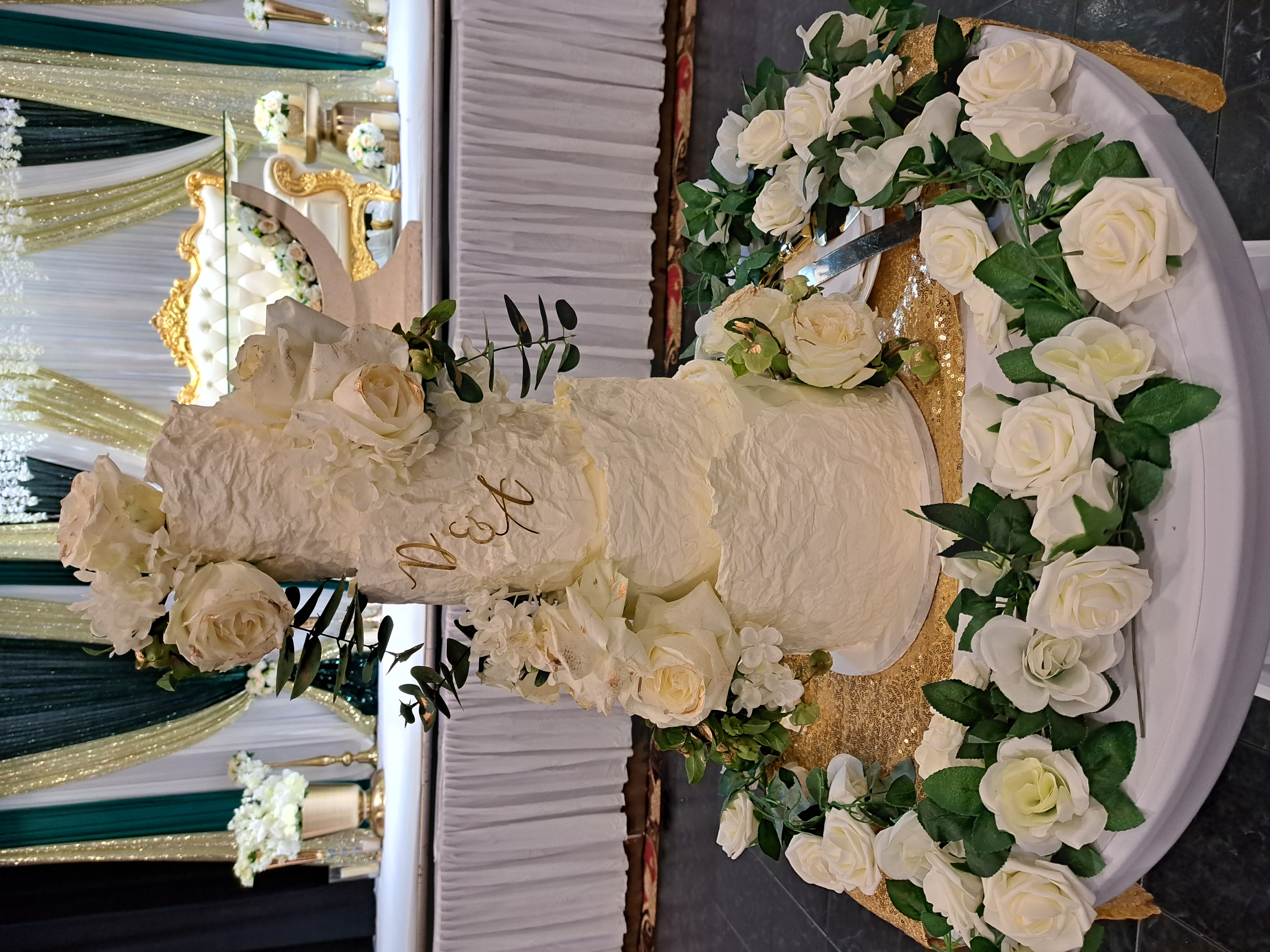 A tall tiered white wedding cake decorated with roses