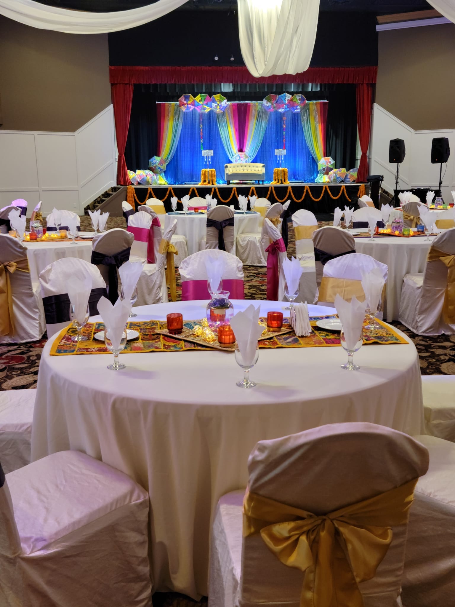 Round tables with gold sashes in front of a lit stage
