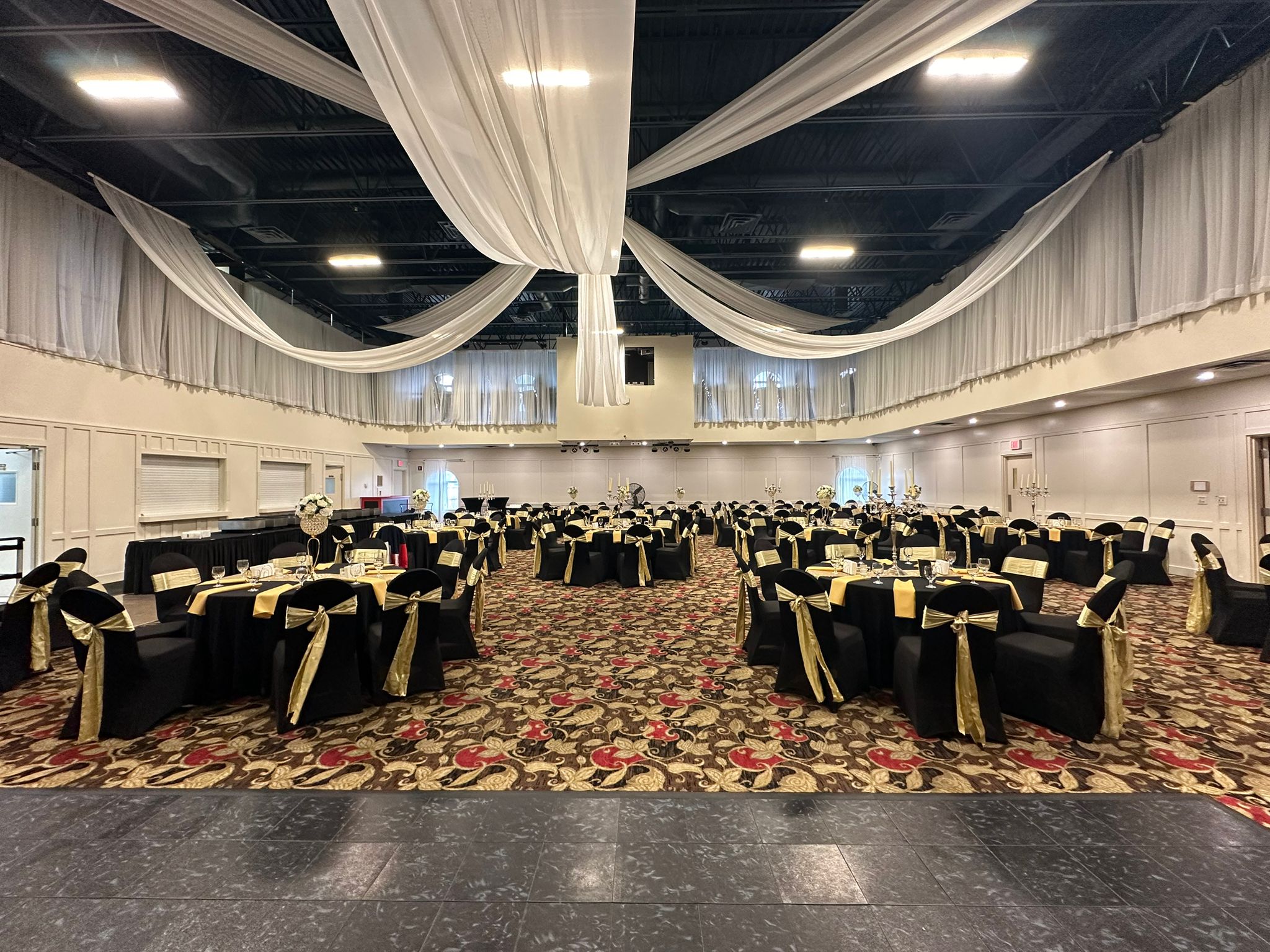 The ACCA hall set with round tables and gold sashes under white ceiling draping, before guests arrive