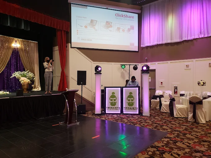 A projection screen and podium on the ACCA stage with purple uplighting