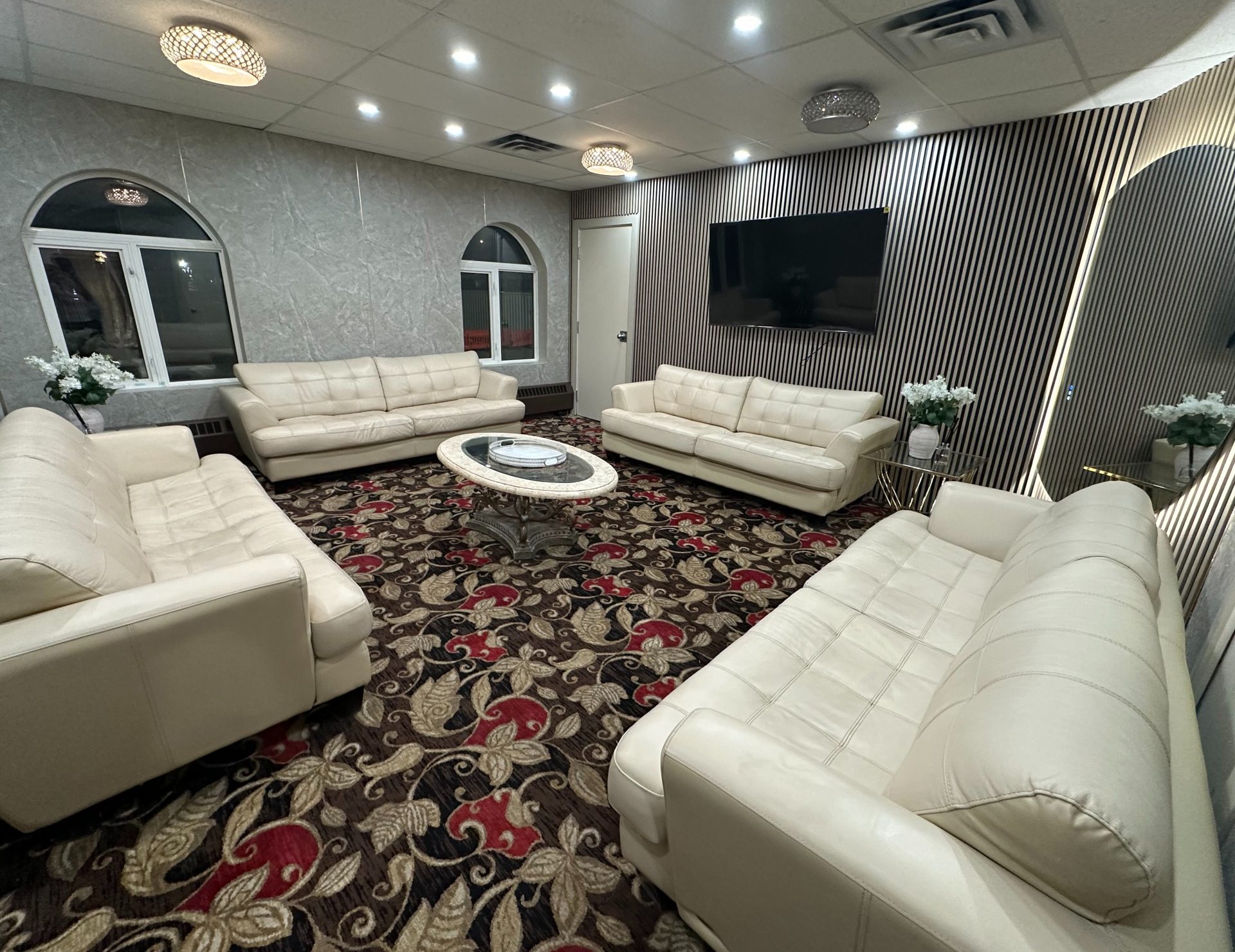 The Private Event Suite with white leather sofas and a wall-mounted screen
