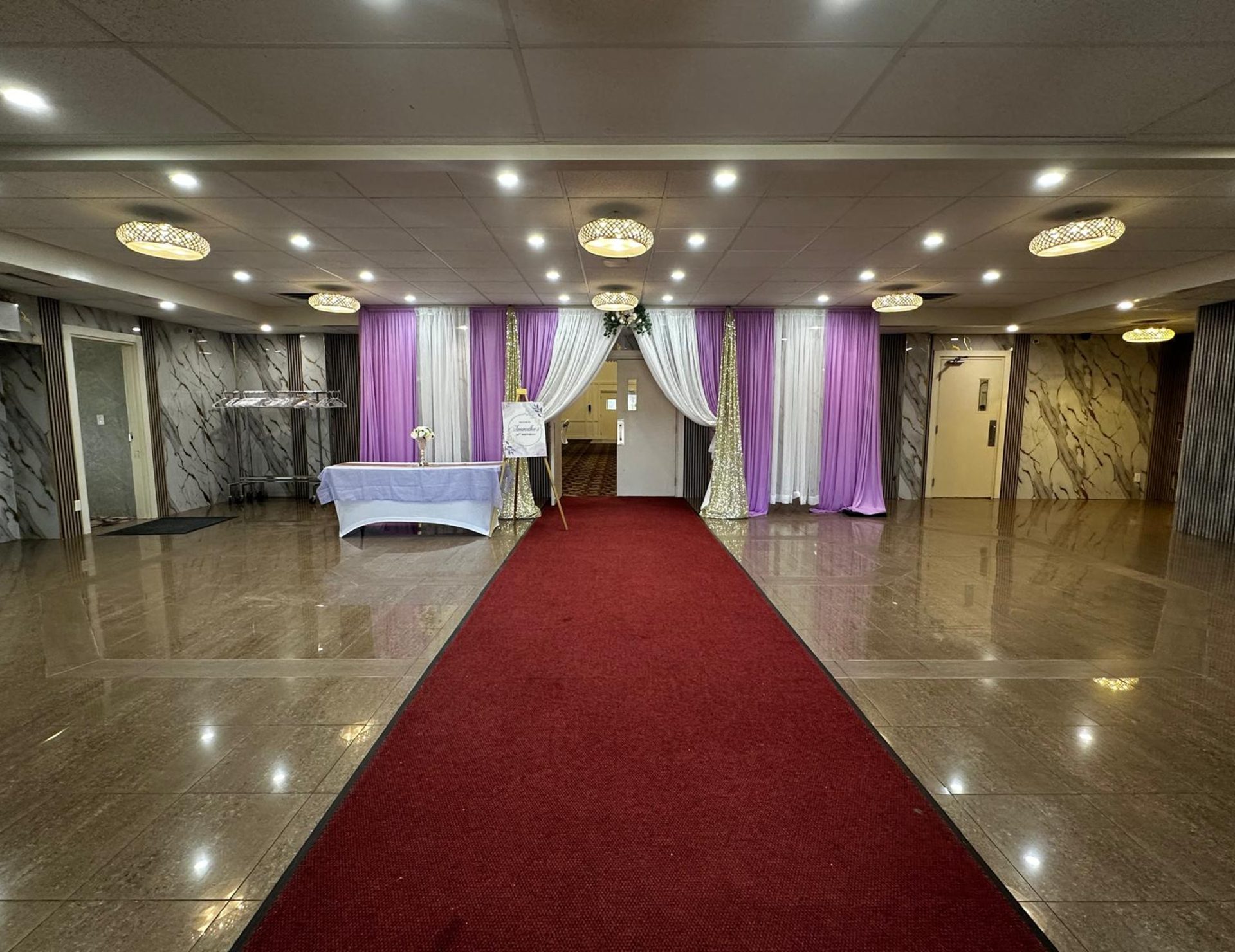 A red carpet aisle running between lilac draped walls in the ACCA hall