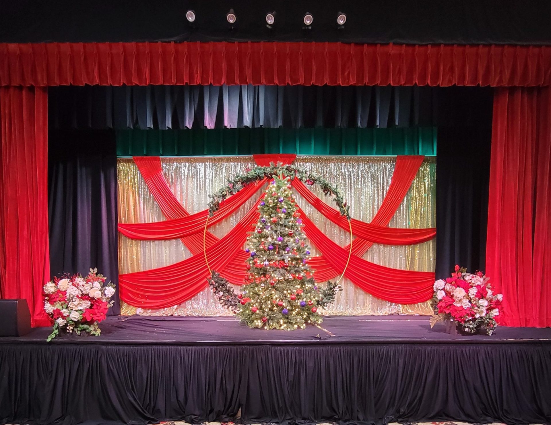 A red draped stage with a cascading floral display and garlands