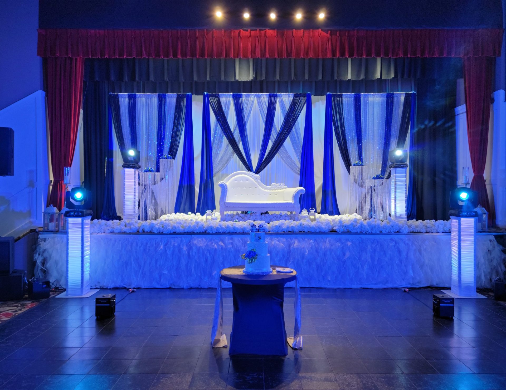 A blue uplit stage with the wedding cake on a central table