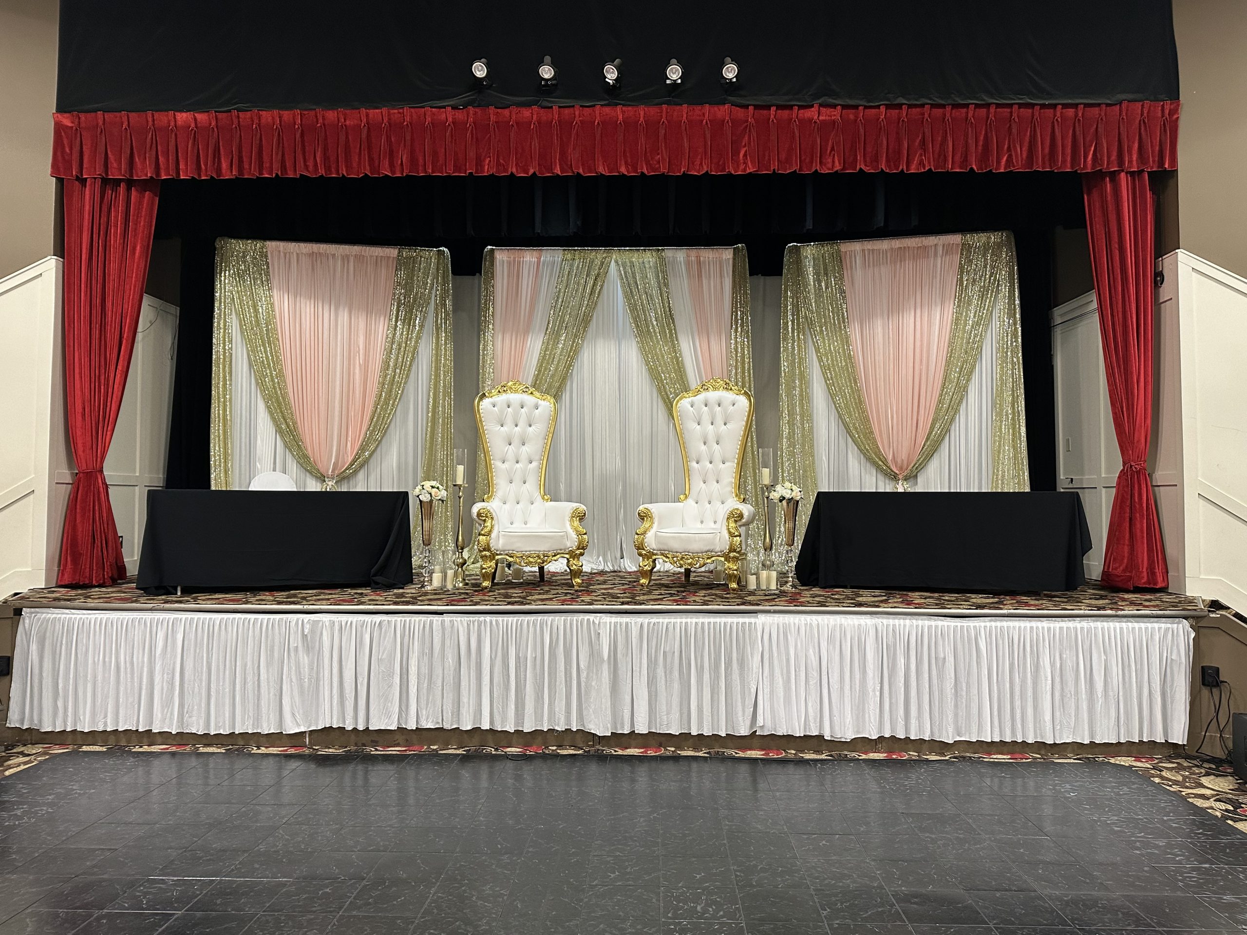 A red and cream draped stage with a white head table
