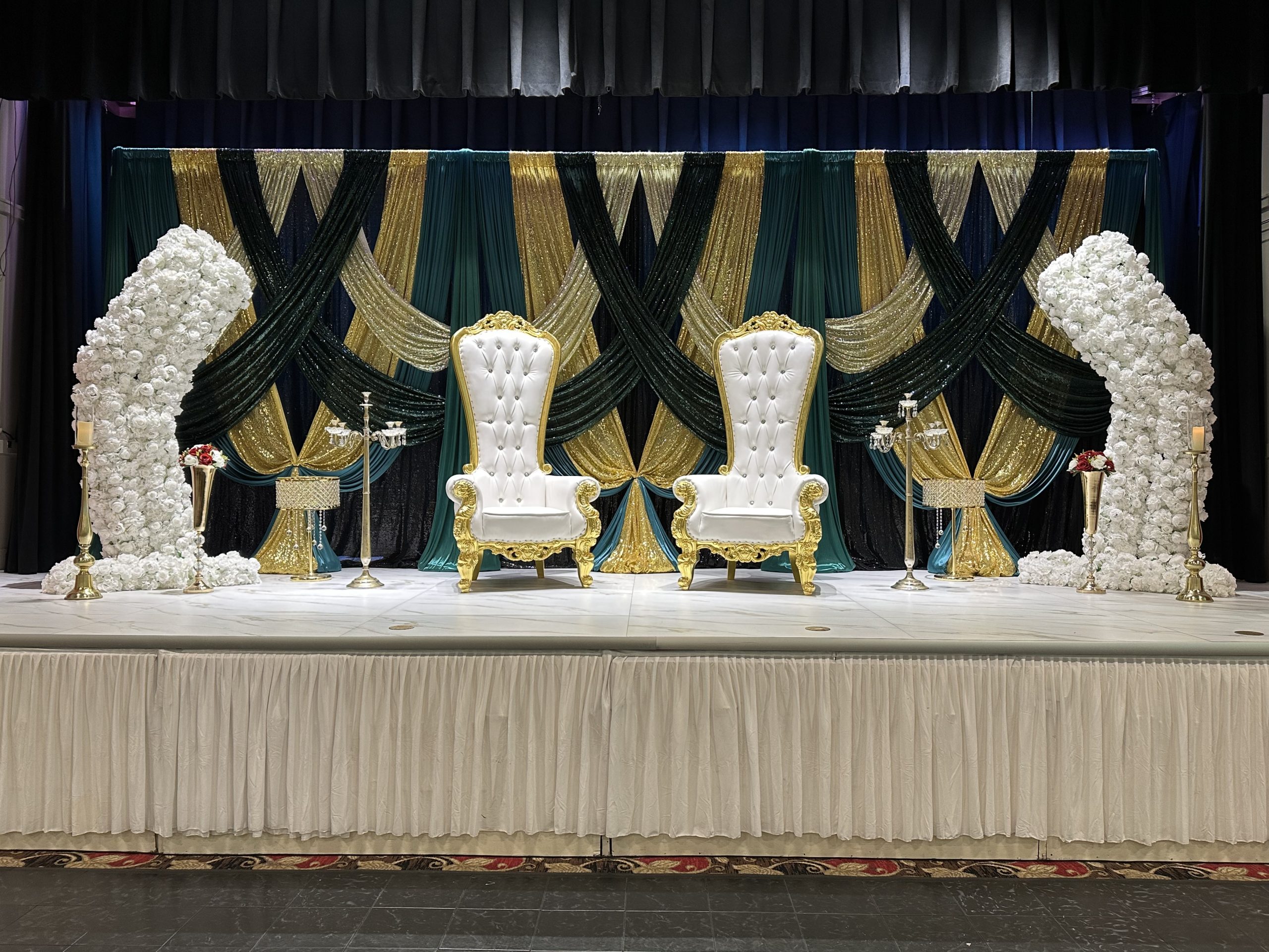 A white and black stage with tall sculpted floral columns