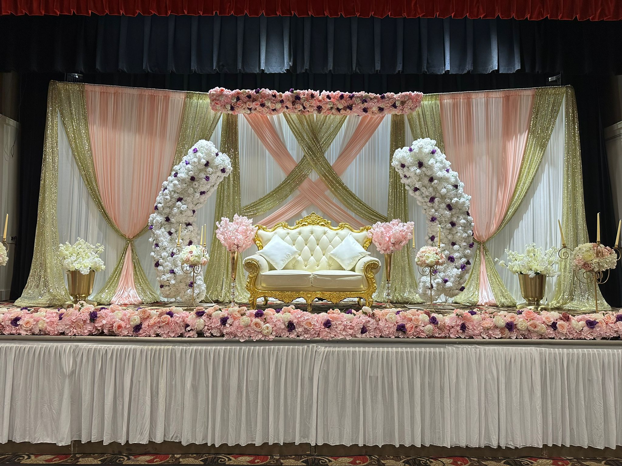 A blush floral stage with a cream settee and rose garlands