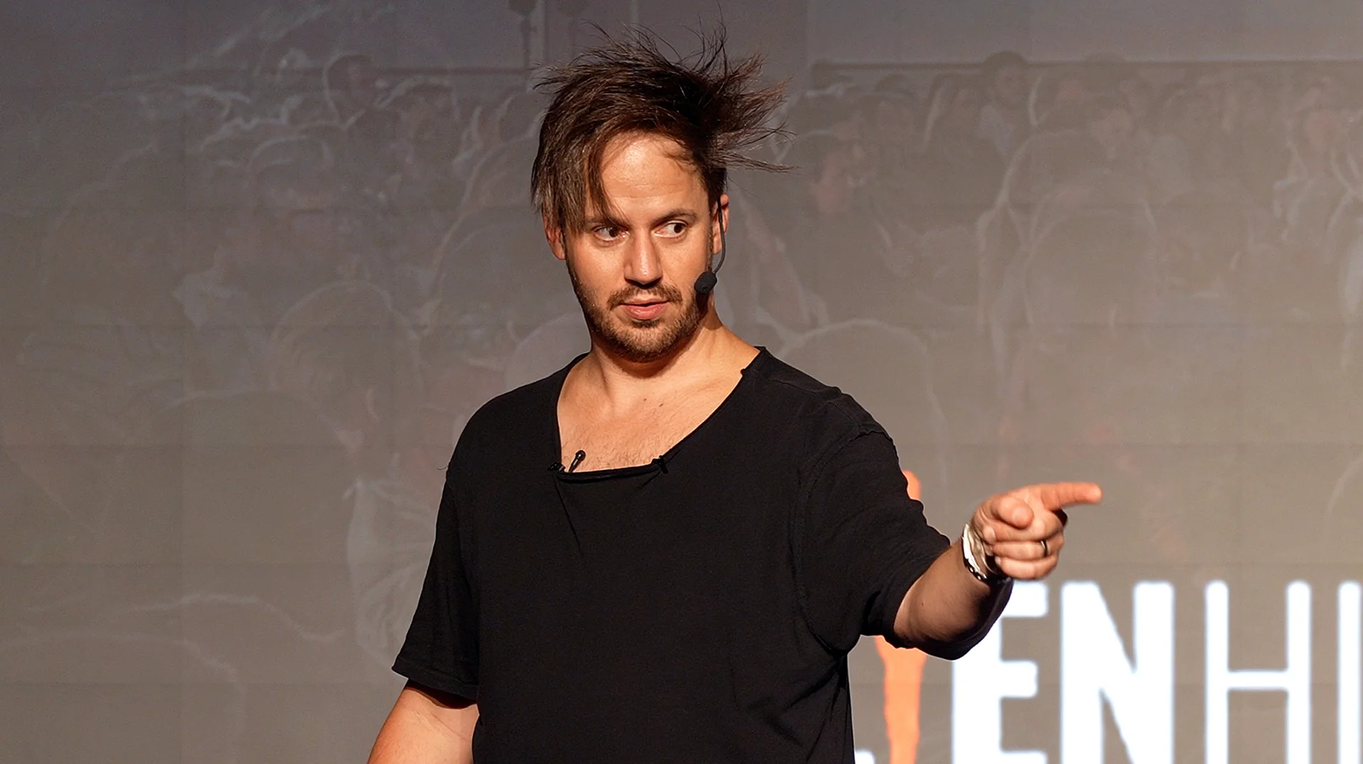Julien Blanc speaking on stage with a headset microphone
