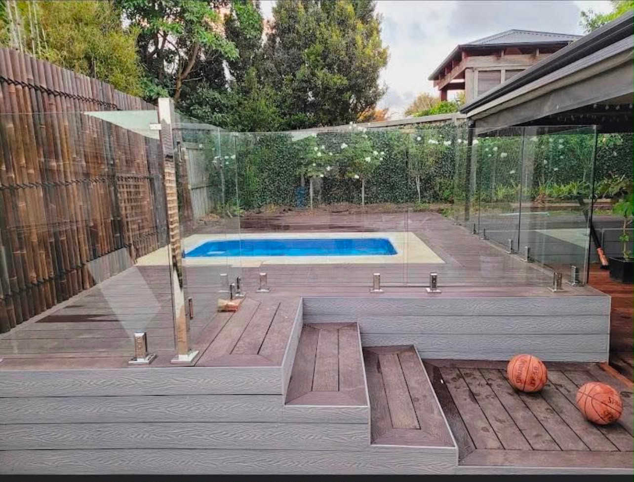 Multi-level poolside decking with steps and glass pool fencing