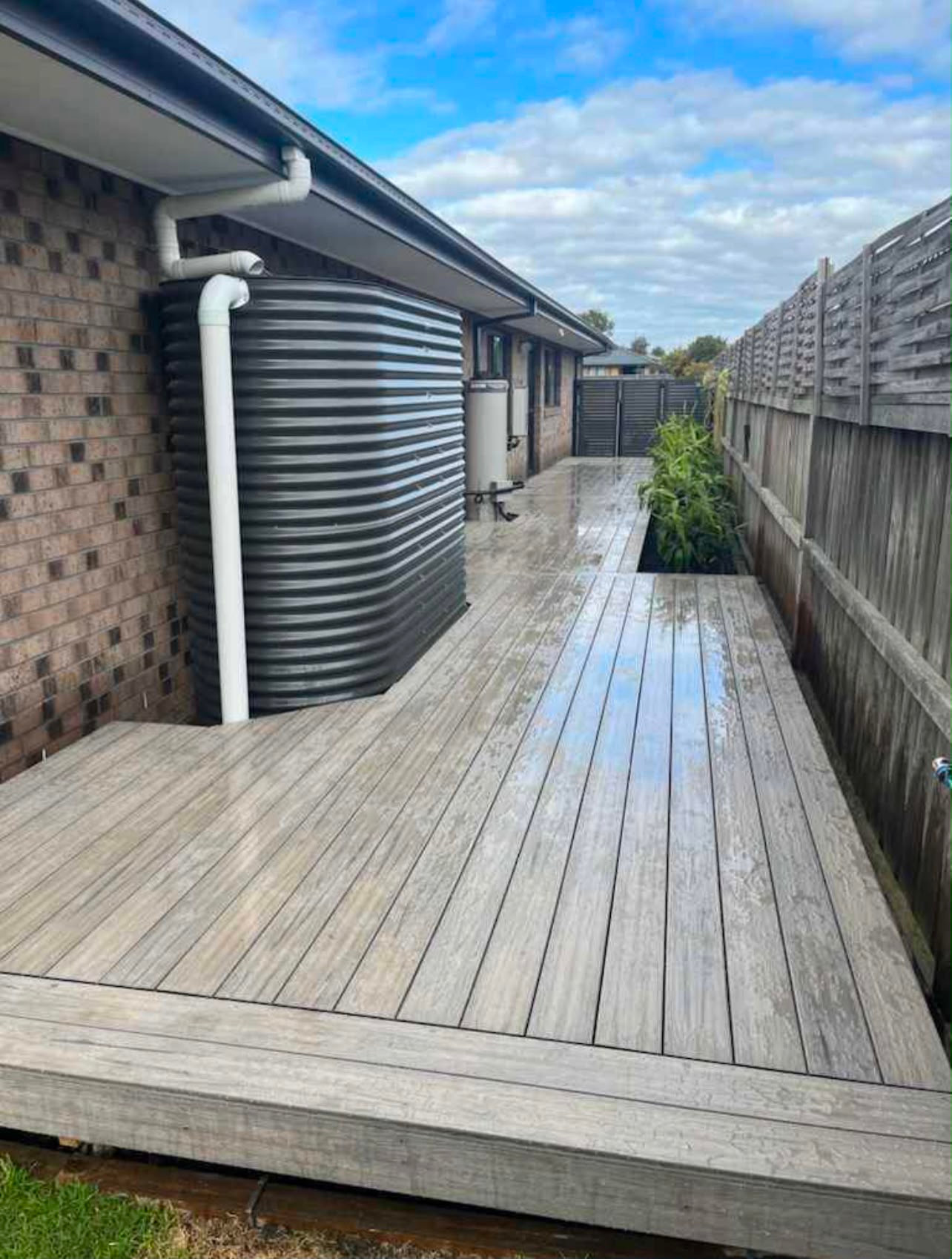 Grey side-yard decking with a planted border alongside the fence