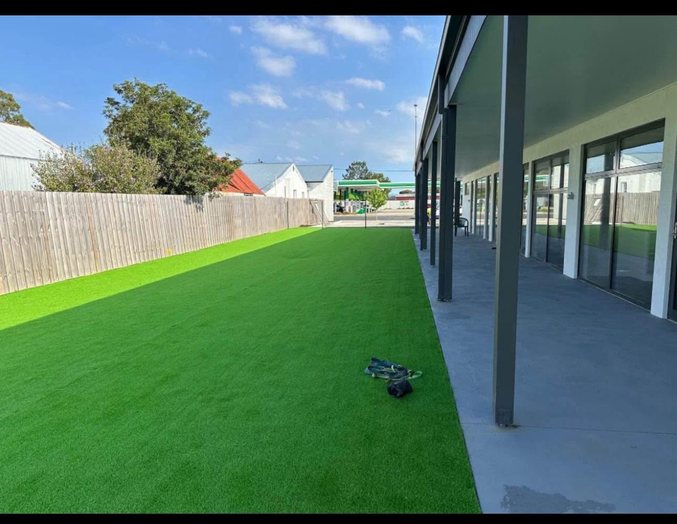 Childcare outdoor area with green landscaping beside a covered concrete walkway