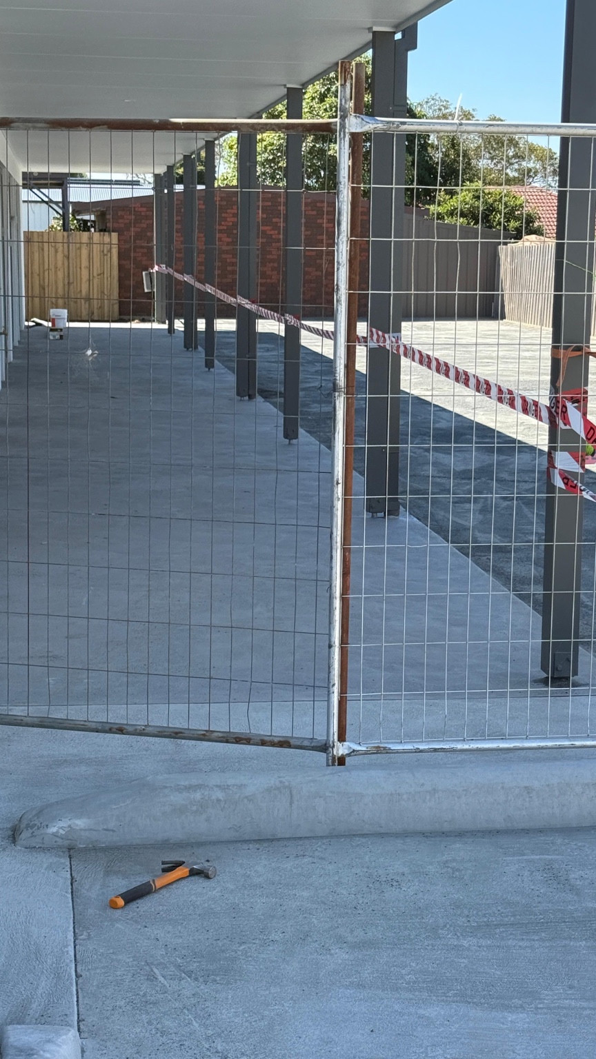 Concrete works at a childcare site viewed through temporary construction fencing
