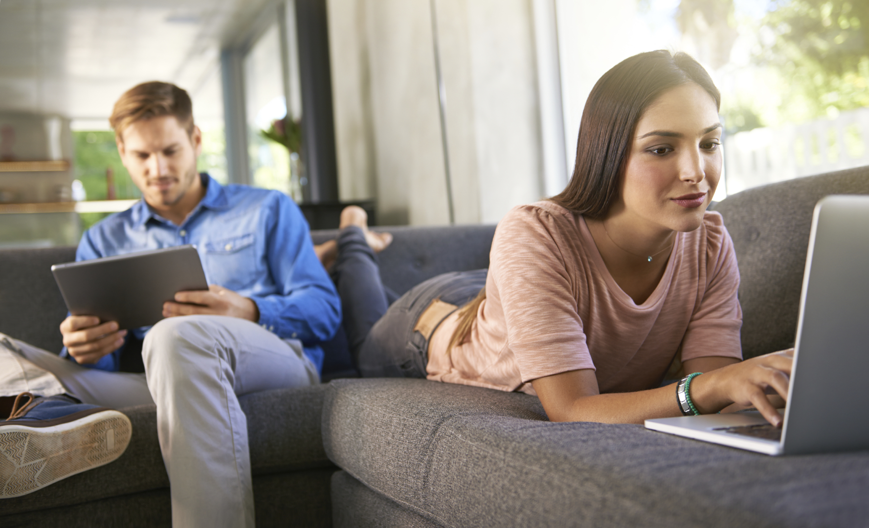 Male and Female couple on the couch with tablets