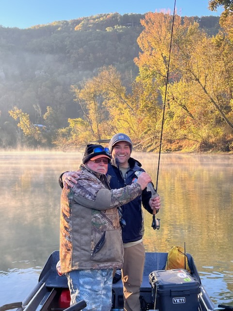 Fly fisherman wading in scenic mountain river at sunrise