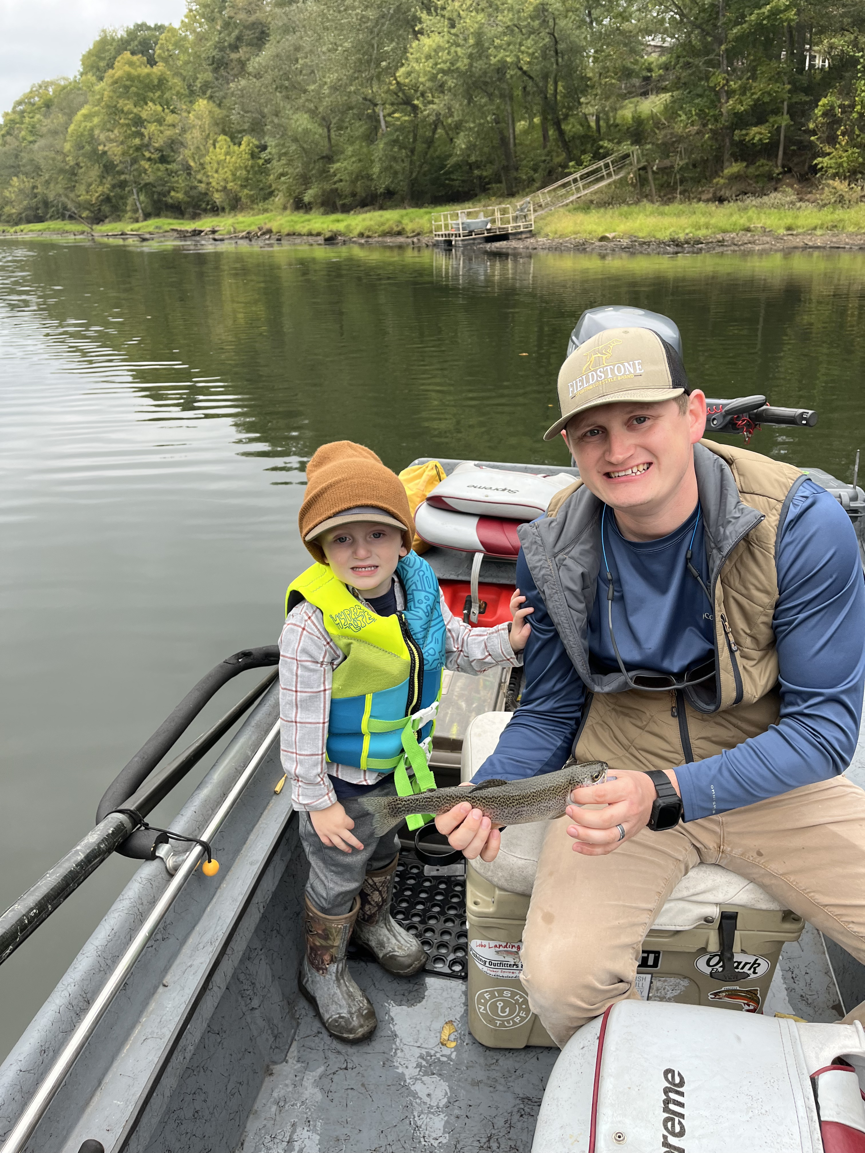 Drift boat fishing on scenic river with angler catching large trout