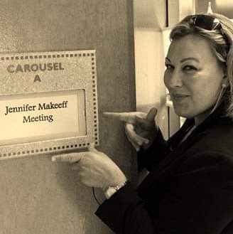 Jennifer Makeeff pointing to a meeting room sign with her name on it