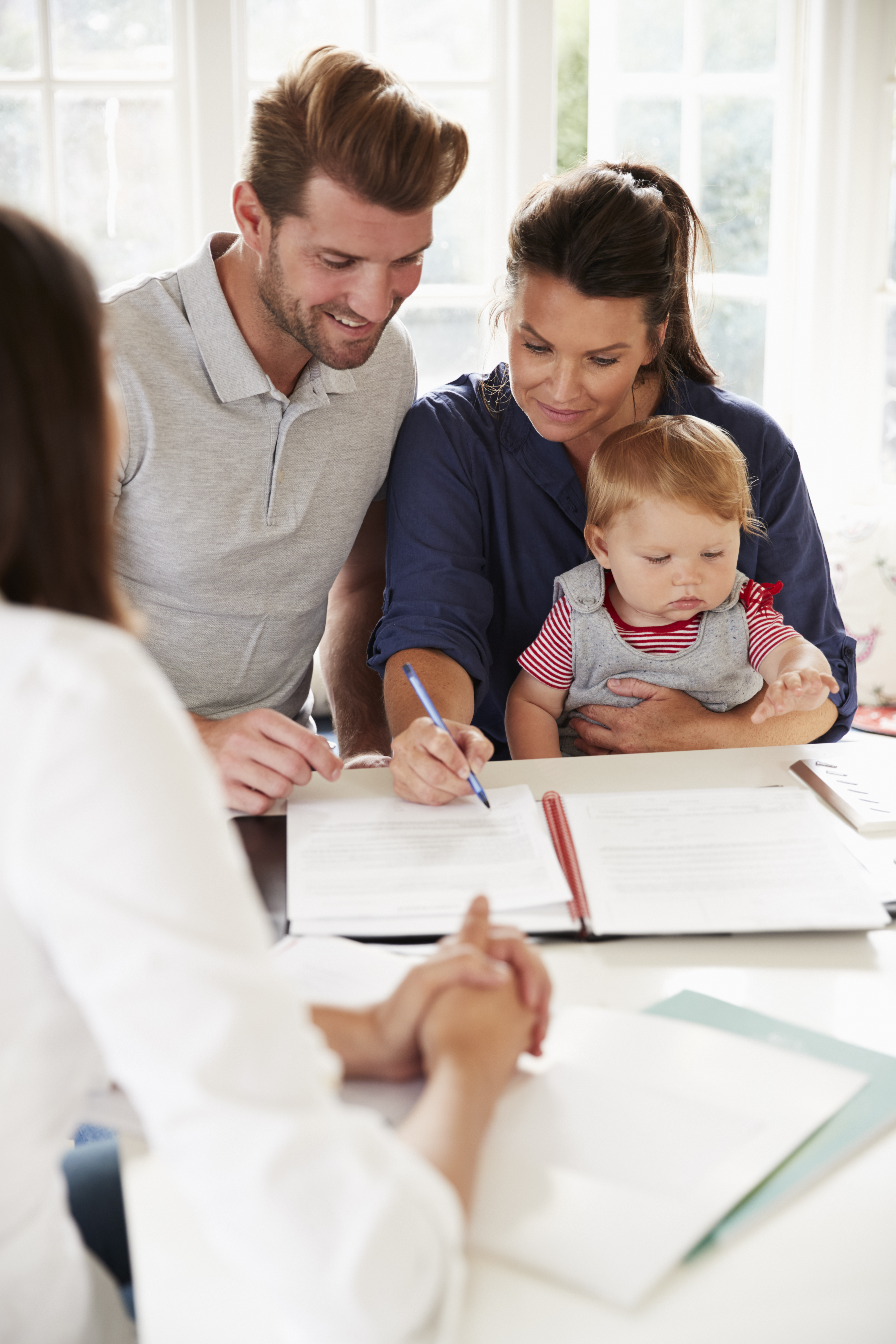 Familia con bebé reuniéndose con un asesor financiero en casa Familia con bebé reuniéndose con un asesor financiero en casa