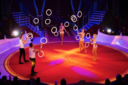 Circus Vargas performers juggling illuminated rings under the big top