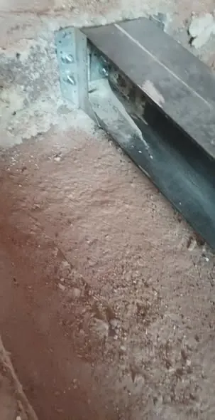 A képen a Farkas-Konstrukt Kft. generálkivitelezési munkálatai láthatók Győr városában. Az építkezés során elhelyezett fém vezetősín részletei jól megfigyelhetők a poros alapzaton. A háttérben a falak textúrája és a burkolat előkészítése is észlelhető, ami a professzionális kivitelezés minőségét tükrözi.