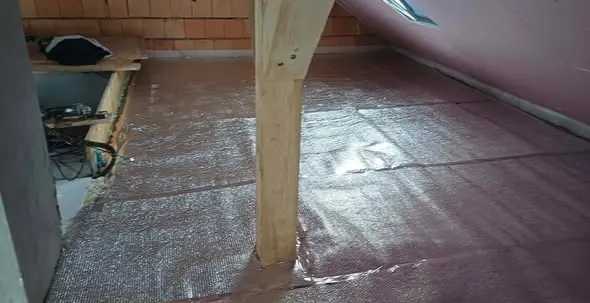 A képen egy építkezési helyszín látható, ahol a padló felújítása zajlik. Az aljzatburkolat alatt védőfólia található, amely a nedvesség ellen véd. A falon látható fáklyák és gerendák a szerkezet biztosítását szolgálják. A Farkas-Konstrukt Kft. Generálkivitelezés tevékenysége Győr városában zajlik, ahol a minőségi kivitelezés a fő szempont.