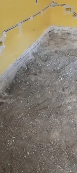 A képen egy építkezés fázisa látható, ahol a padló még nincs kész, és földes, kavicsos alap található. A falon sárga festés látható, amely friss és új, jelezve a családi ház tervezésének folyamatát. A Farkas-Konstrukt Kft. Generálkivitelezés szolgáltatása Győr városában valósul meg, ahol a belső terek kialakítása zajlik.