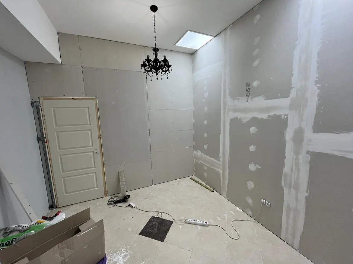 Győr városában a Farkas-Konstrukt Kft. generálkivitelezési szolgáltatása keretében készült családi ház belső terének látképe látható. Az elkészült falak gipszkartonból készültek, és a mennyezetről egy elegáns csillár lóg. A padló burkolata világos, míg a falakon csak a gipszkartonok szerelésére utaló jelek láthatók. A szoba világos és tágas, a tervezett helyiségek kialakítása még folyamatban van.