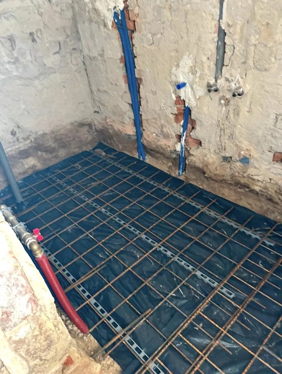 A képen a Farkas-Konstrukt Kft. generálkivitelezési szolgáltatásának keretein belül végzett betonozási előkészületek láthatók Győr városában. Az alapozás alatt látható acél rácsozat, amely biztosítja a jövőbeli beton stabilitását. A falakon vízvezetékek és egyéb szerelések helyezkednek el, ami a kivitelezés részletességét tükrözi.