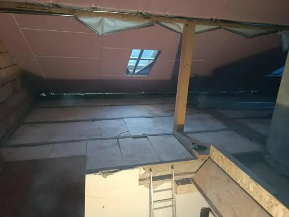 A képen egy építkezés látható, ahol a tetőtér szigetelése folyik. A nyitott tetőablak és a látszó gerendák jól mutatják a Generálkivitelezés folyamatát. A Győr városában található Farkas-Konstrukt Kft. által végzett munka precíz és részletes, a helyszínen lévő létra pedig a munkálatokhoz való hozzáférést segíti elő.