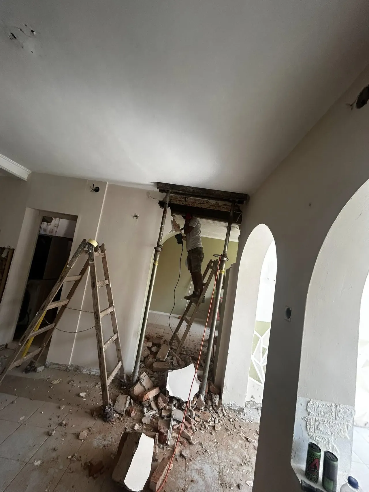 Egy felújítás alatt álló belső tér látható, ahol a Farkas-Konstrukt Kft. generálkivitelezési szolgáltatását végzik Győr városában. A képen egy munkás létrán állva végez munkát, miközben a falak körül törmelék található. A szoba még nem készült el, a falak festésre várnak, és az építkezési anyagok is fellelhetők a helyiségben.