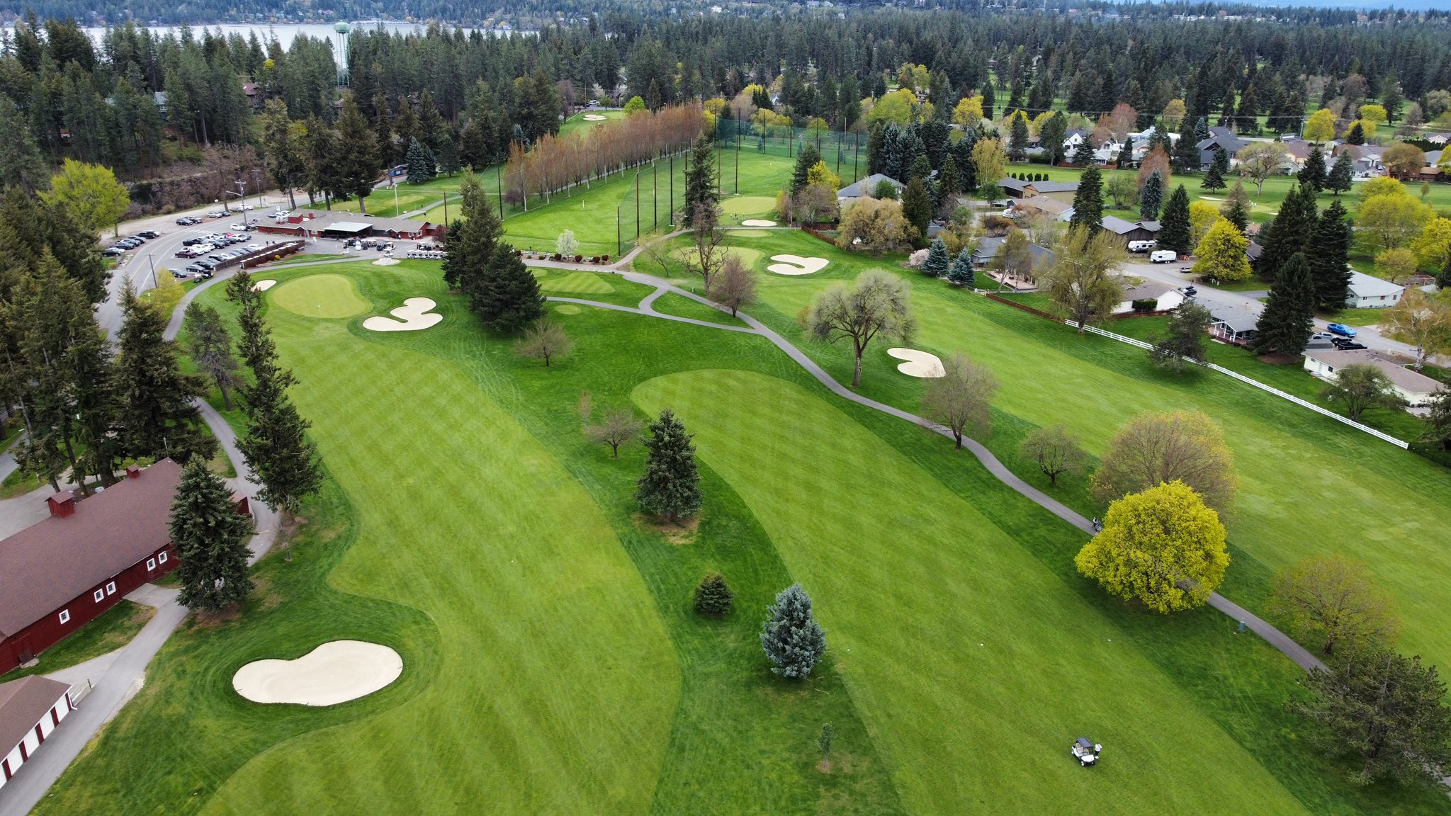 Aerial view of a lush green golf course at golden hour with manicured fairways and bunkers