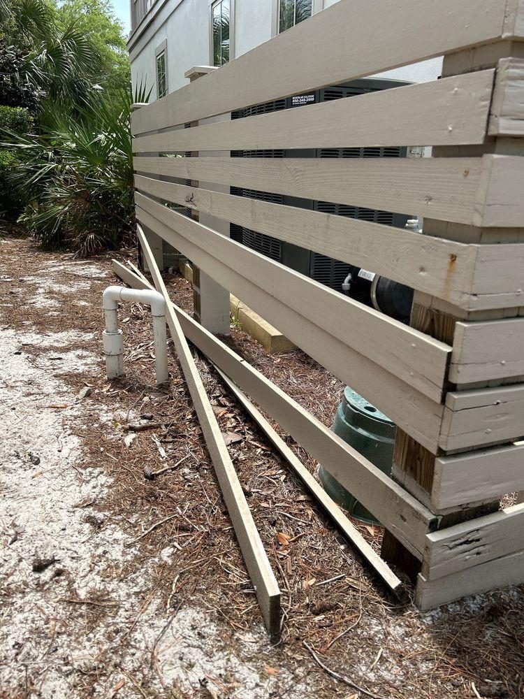 Exterior air conditioning condenser surround fence with multiple horizontal wooden slats fallen off and lying on the ground