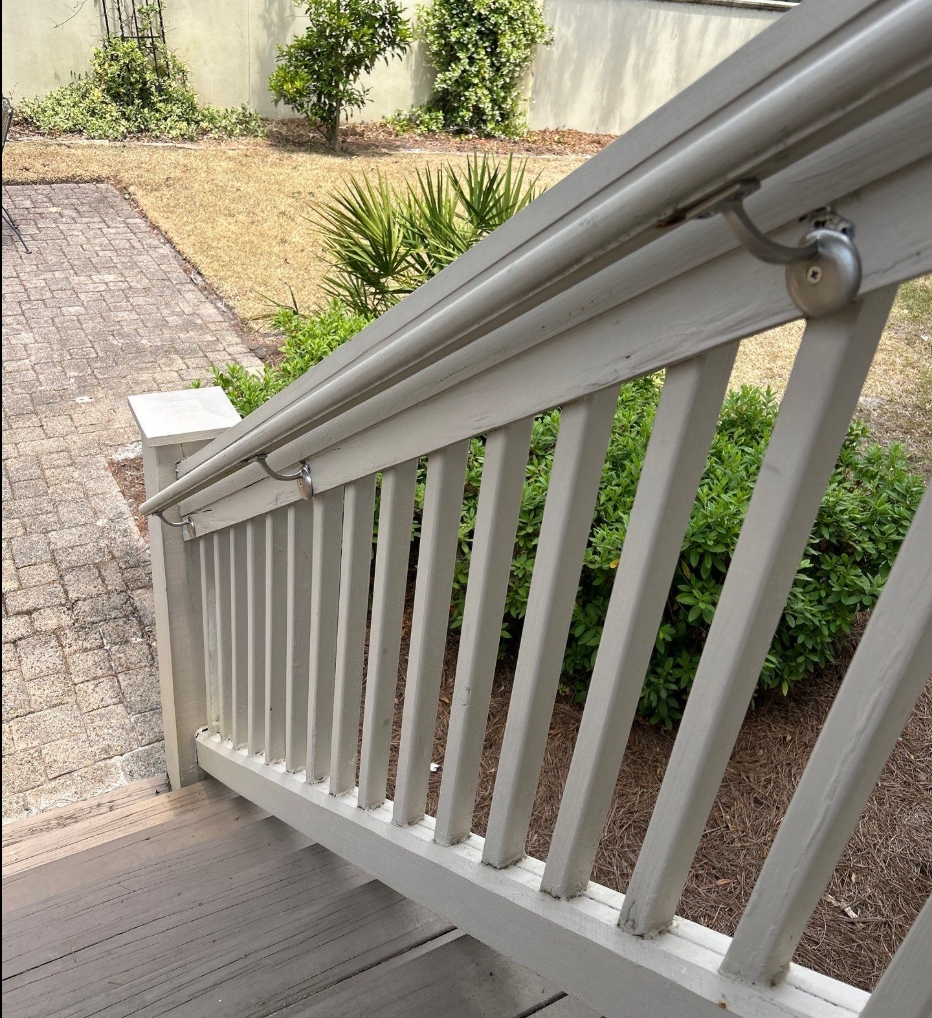 Newly installed stainless steel handrail bracket hardware securing a freshly reinforced handrail mount on an exterior staircase