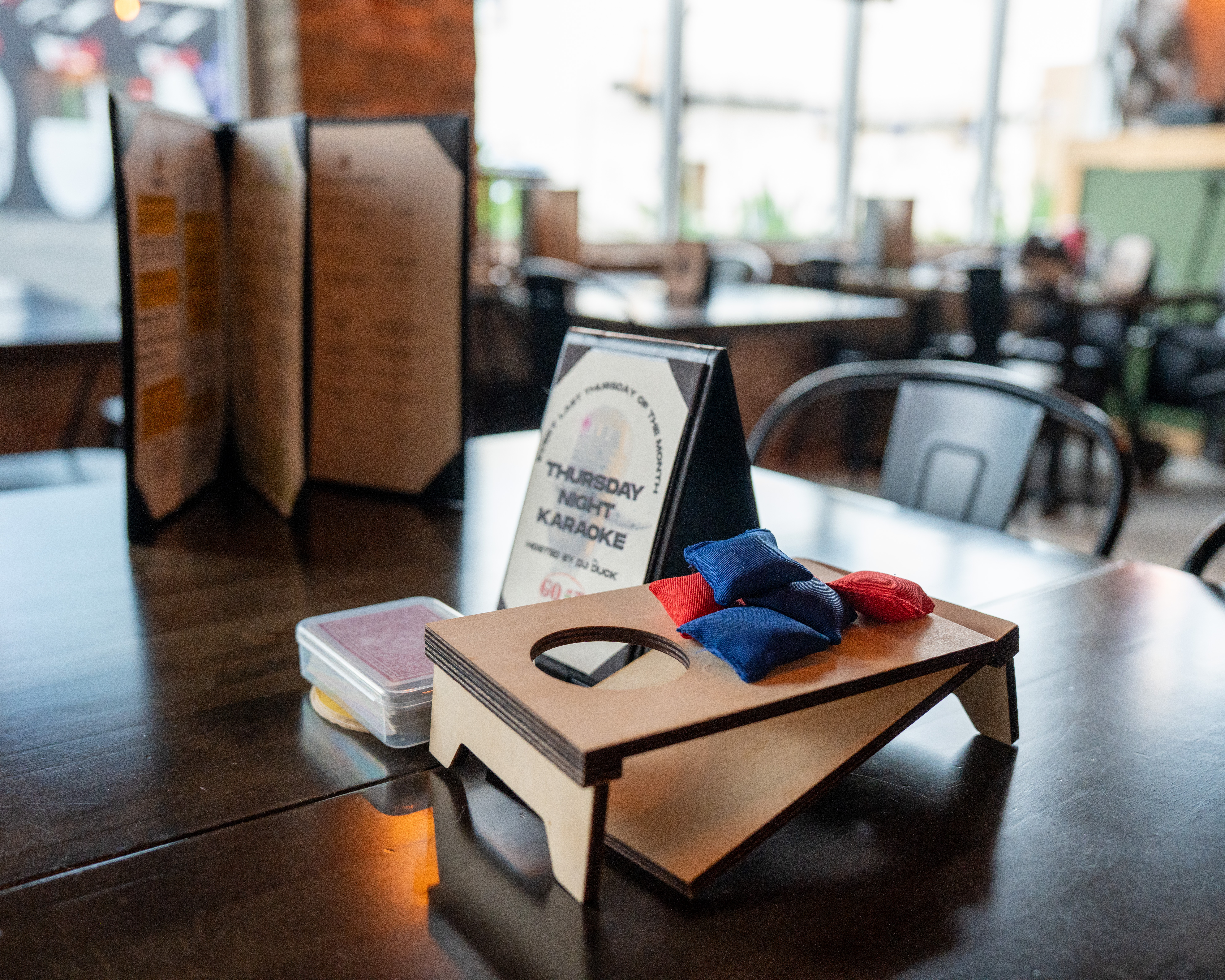 A group table set up with games, cards and menus at Hold My Beer Kenosha