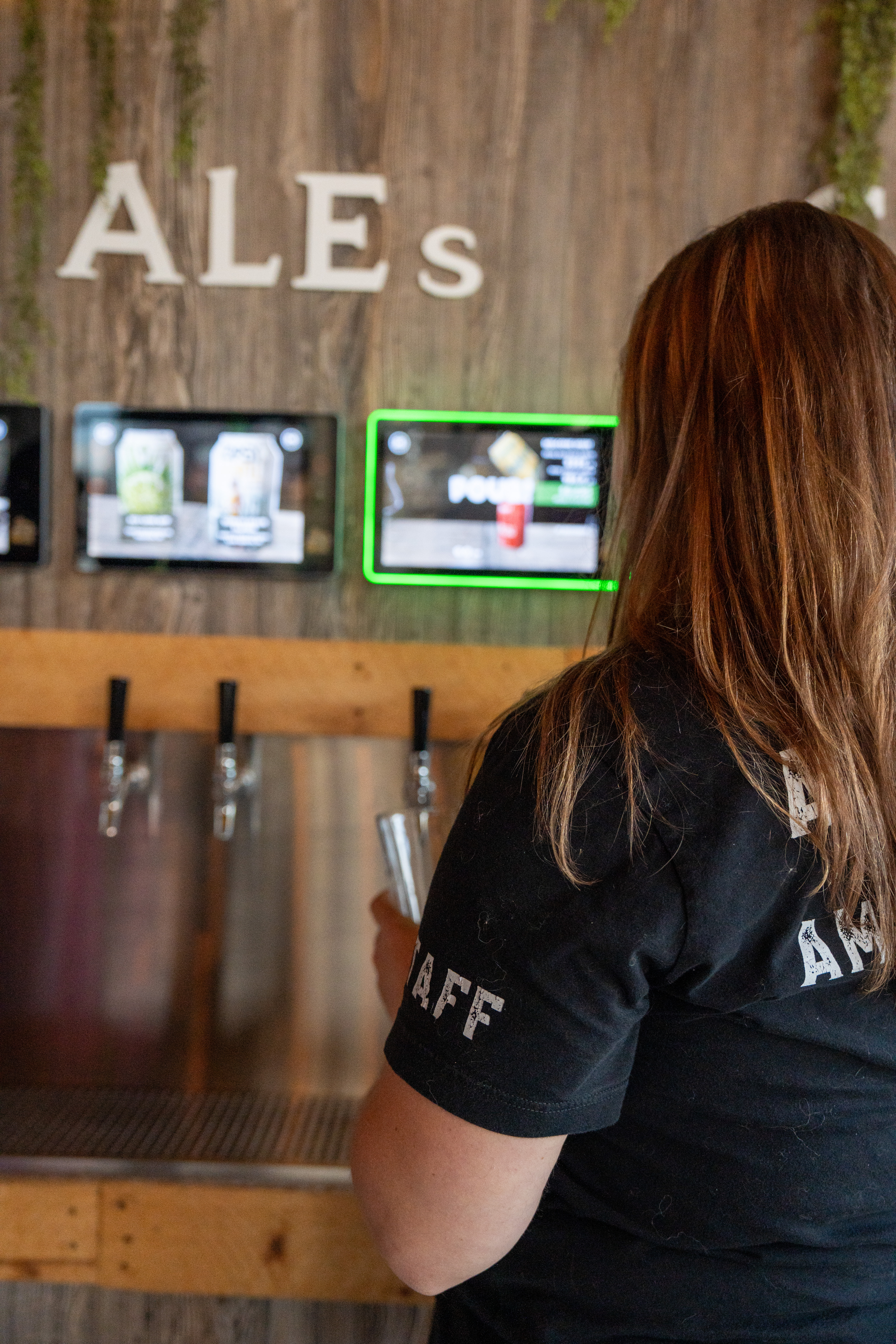 A guest at the 50-tap self-pour beer wall inside Hold My Beer Kenosha