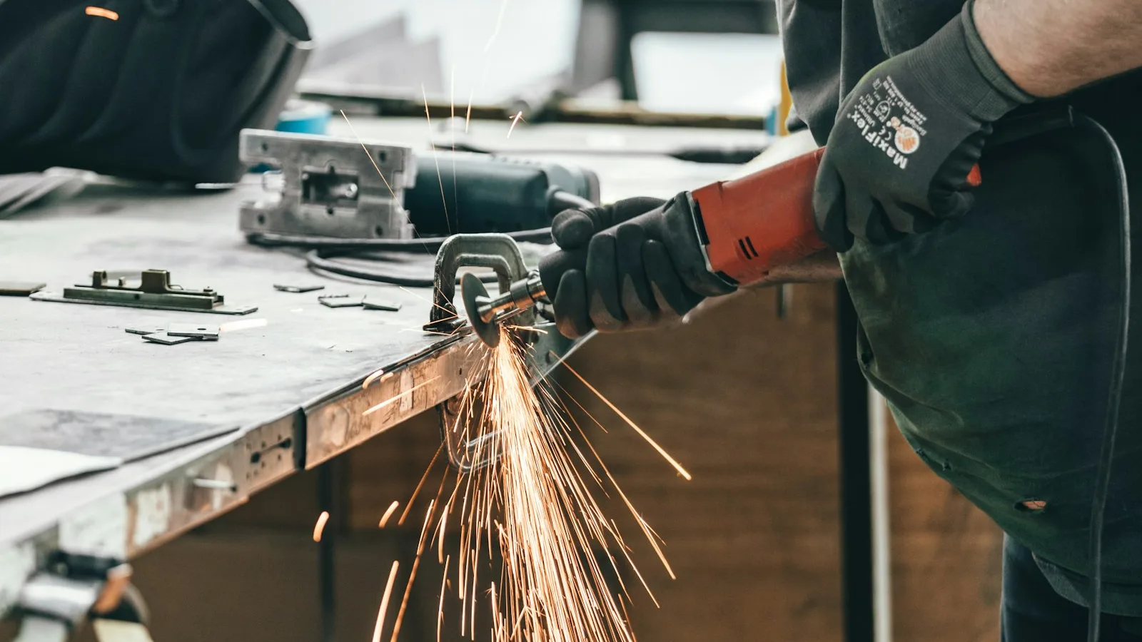 Worker using an angle grinder with sparks in a workshop