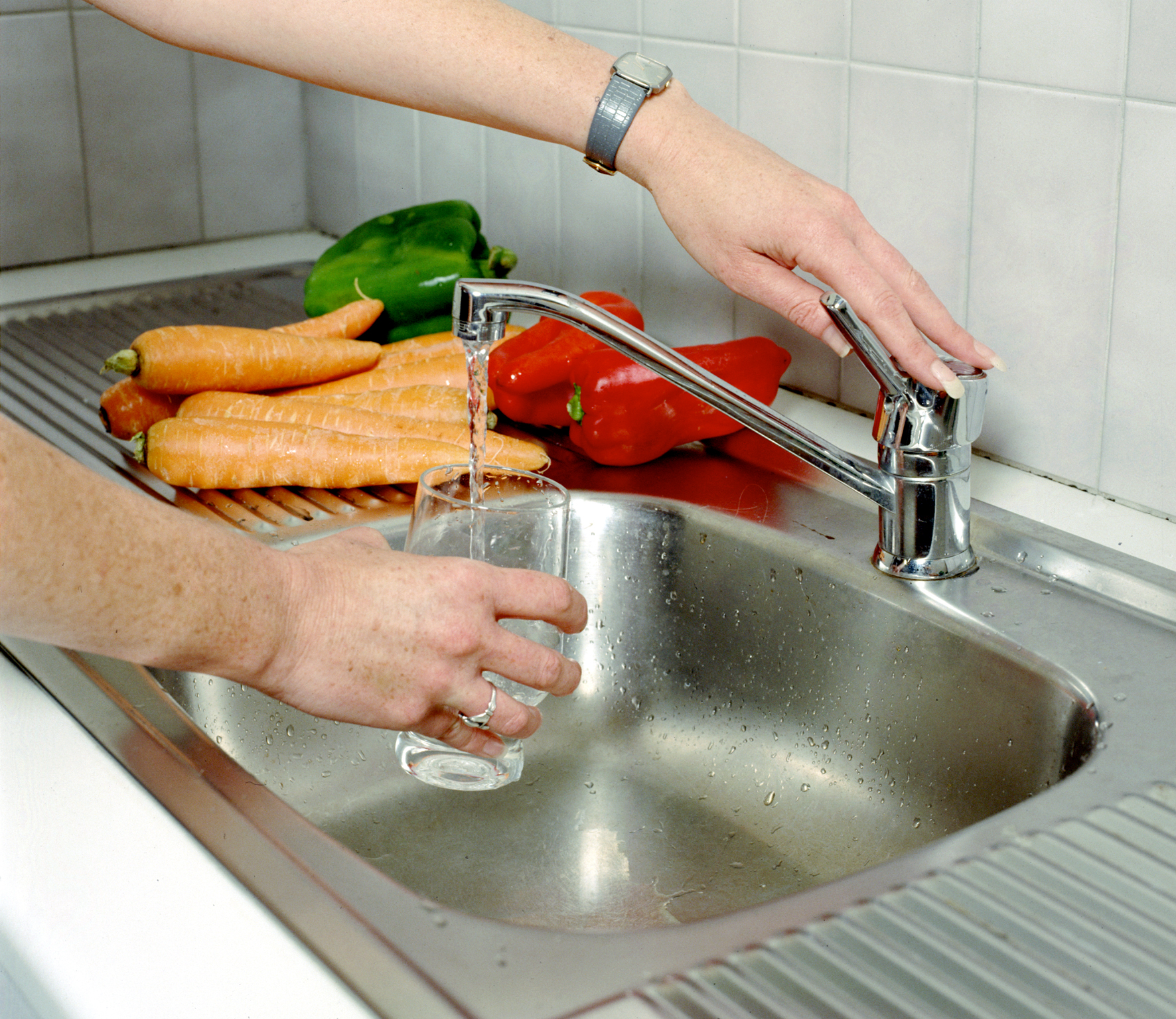 Drinking glass being filled with clear water at kitchen sink