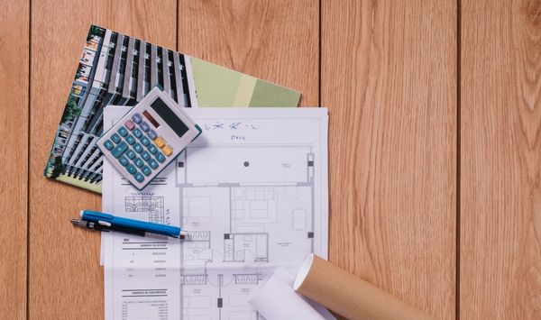 ADU floor plans, calculator, and construction documents on a wooden desk