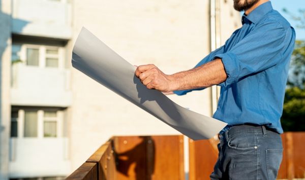 ADU contractor holding construction plans outside a residential property during the planning and building process.