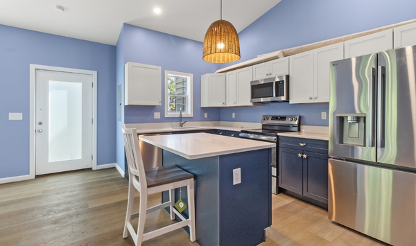 Modern Connecticut ADU kitchen with blue cabinetry, stainless steel appliances, island seating, and bright natural light.