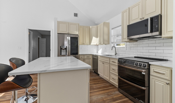 Modern Connecticut ADU kitchen with cream cabinets, marble-look island, stainless steel appliances, and wood flooring Modern Connecticut ADU kitchen with cream cabinets, marble-look island, stainless steel appliances, and wood flooring
