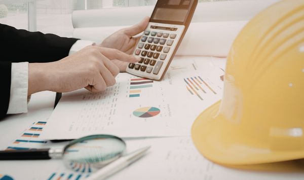 Contractor calculating ADU construction costs in Connecticut with building plans, financial charts, and a hard hat. Contractor calculating ADU construction costs in Connecticut with building plans, financial charts, and a hard hat.