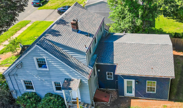 Aerial view of a two-story house beside a single-story residential addition, showing rooflines and site layout relevant to ADU planning.