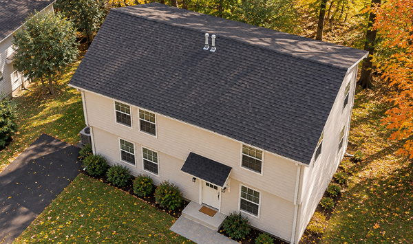 Bird's-eye view of a two-story ADU design showing the roof, compact building footprint, entrance, and surrounding yard.