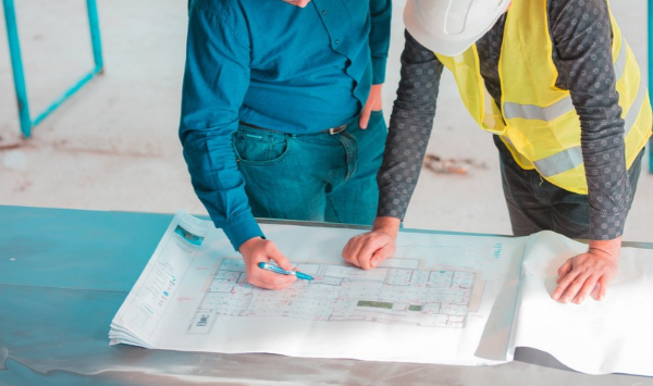 Construction professionals reviewing architectural blueprints for residential building planning. 