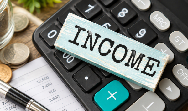 Calculator with coins and an income sign representing potential ADU rental income and return on investment. 