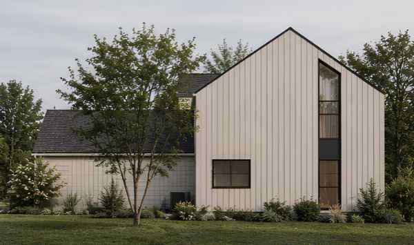 Side view of a contemporary white home with vertical siding, black-framed windows, steep gable roof, and landscaped lawn.