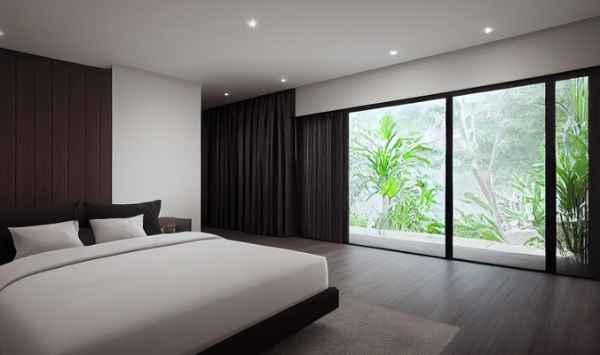 Modern bedroom with a large bed, dark accent wall, and floor-to-ceiling windows overlooking greenery.